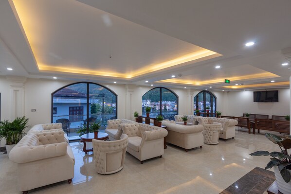 A spacious lobby with a high ceiling, large arched windows, and a seating area with plush sofas and armchairs. - Sapa Passion Hotel & Spa (Sa Pa)