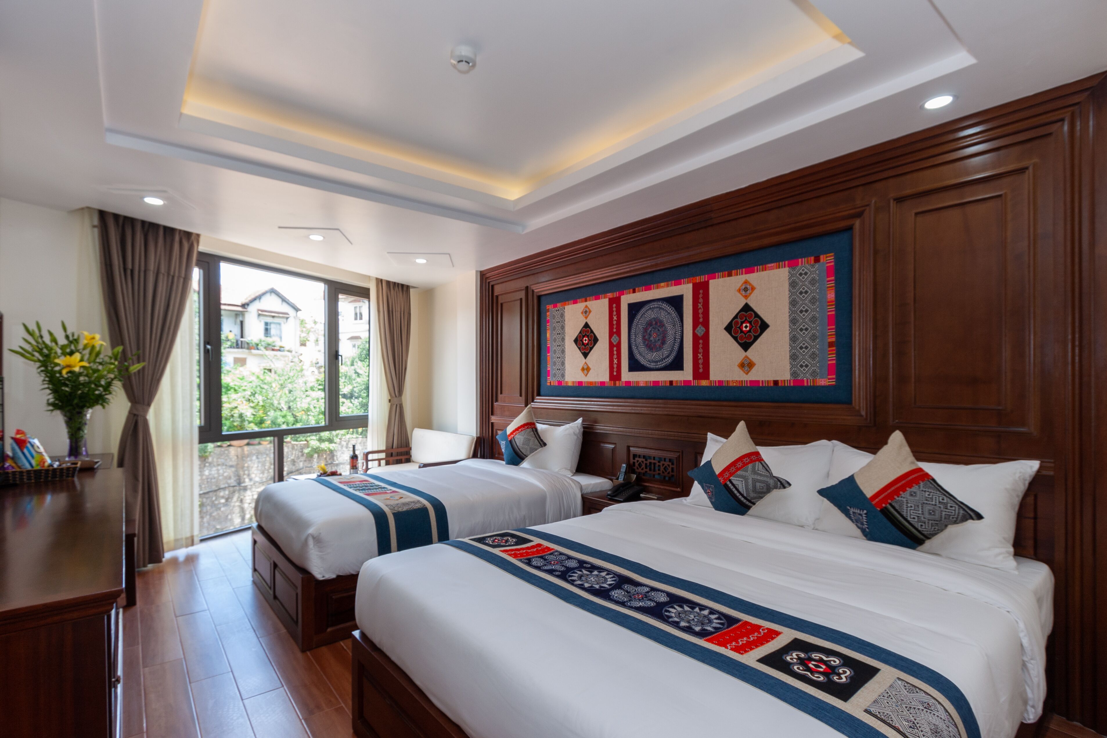 A hotel room with two beds, a wooden headboard, a large window, and a view of the outside.