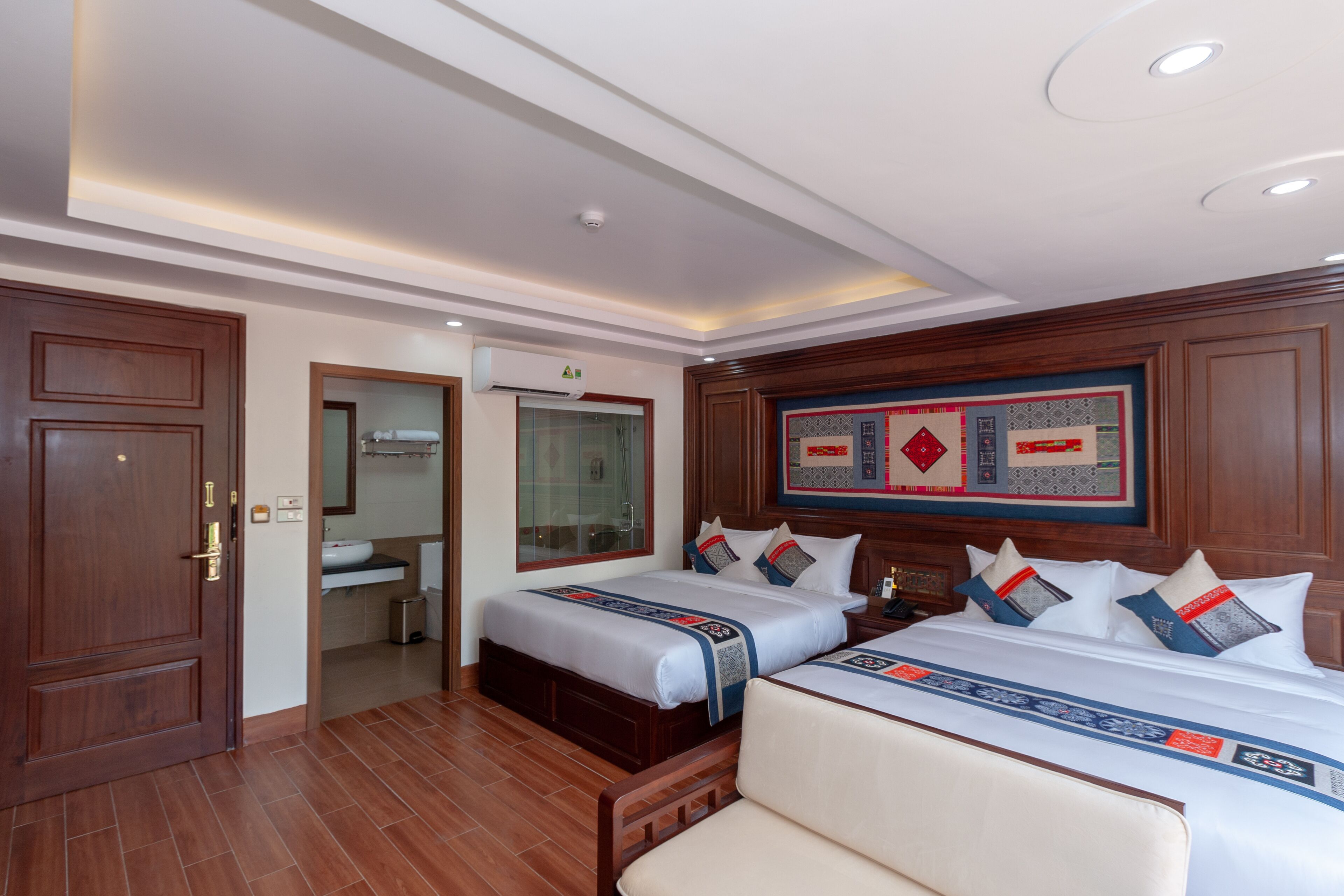 A hotel room with two beds, a bathroom, and a large decorative wall piece.