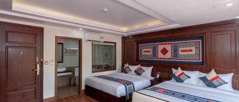 A hotel room with two beds, a bathroom, and a large decorative wall piece.