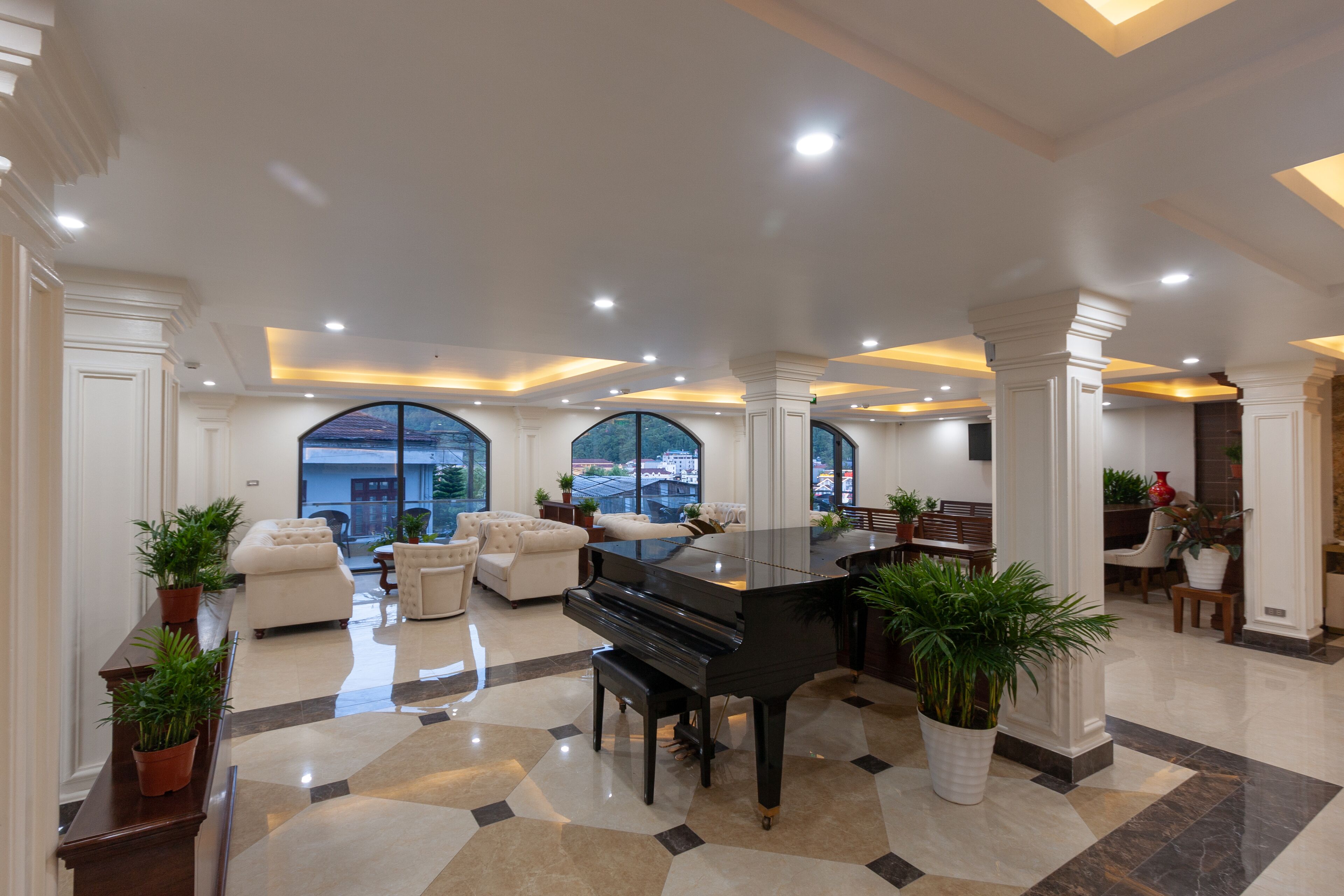 A spacious living area with a grand piano, comfortable seating, large windows, and a modern interior design.