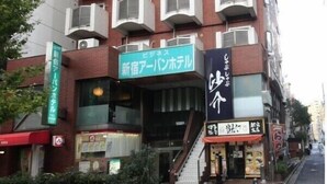A multi-story building with a central entrance, multiple balconies, and signage for a hotel and other businesses. - Shinjuku Urban Hotel (Tokyo)
