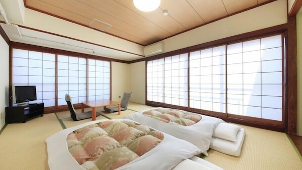 A traditional Japanese-style room with tatami flooring, two tatami beds, a television, and sliding doors. - Shinjuku Urban Hotel (Tokyo)