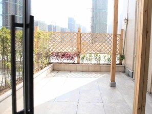 Un balcón con un panel de celosía de madera, plantas en macetas y vista panorámica de la ciudad.