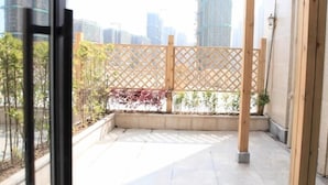A balcony with a wooden lattice partition, potted plants, and a cityscape view. - Greentree Inn Anqing Duxiu Avenue Greenland Metrop (Anqing)