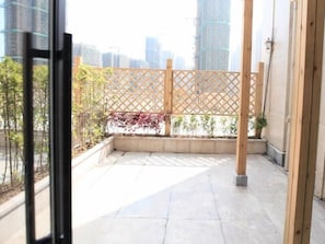 A balcony with a wooden lattice partition, a concrete floor, and a view of a cityscape with tall buildings. - Greentree Inn Anqing Duxiu Avenue Greenland Metrop (Anqing)