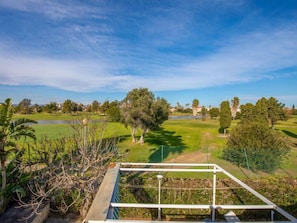 A golf course with a clear sky, a pond, and trees.