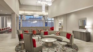 A modern lobby with a curved seating area, a reception desk, and large windows. - Homewood Suites by Hilton Long Beach Airport (Long Beach)