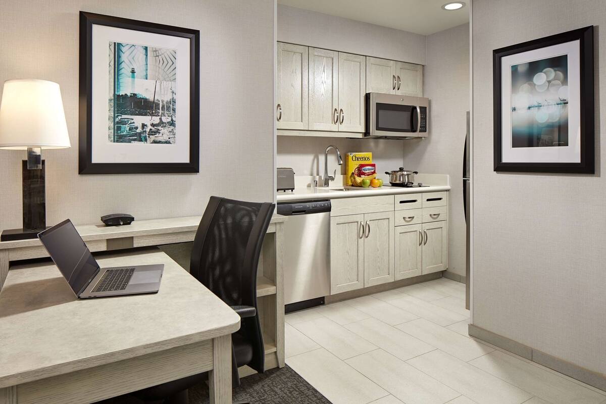 A modern kitchen with a microwave, refrigerator, and a dining area with a laptop on the table.