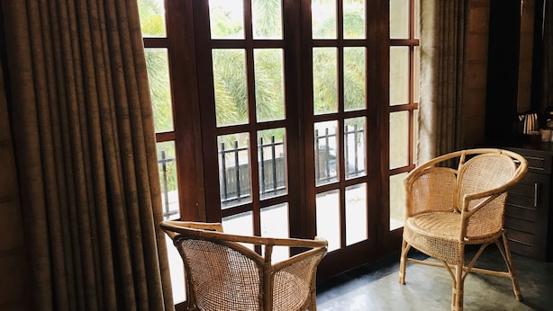 A room with a large window, two wicker chairs, and a wooden cabinet. - Ravan Tangalle (Tangalle)