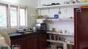 A kitchen with a stove, microwave, and various kitchen utensils. - The Shelter Hotel - Port Blair (Port Blair)