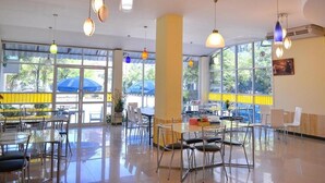 A spacious indoor area with tables and chairs, large windows, and hanging pendant lights. - Ratchaphruek Pavilion (Nakhon Pathom)