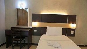 A hotel room with a bed, a desk, and a chair. - Ratchaphruek Pavilion (Nakhon Pathom)