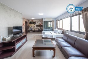 A hotel room with a TV, sofa, bed, and a decorative wall. - Ratchaphruek Pavilion (Nakhon Pathom)