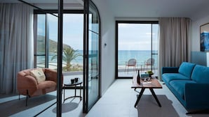Un salon moderne avec vue sur l’océan, un canapé bleu, une cloison en verre et une petite table avec une chaise.