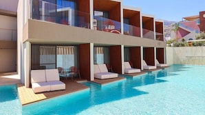 Un hôtel moderne doté d’une piscine, de plusieurs balcons et de chaises longues.