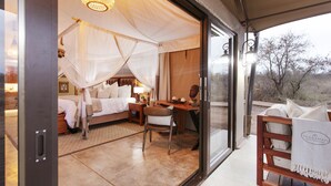 A room with a bed, a desk, and a chair. There is a window with a view of trees.