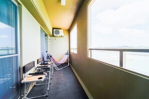 A balcony with a hammock, chairs, and a view of the sea. - Villa Awase 111 (Okinawa)