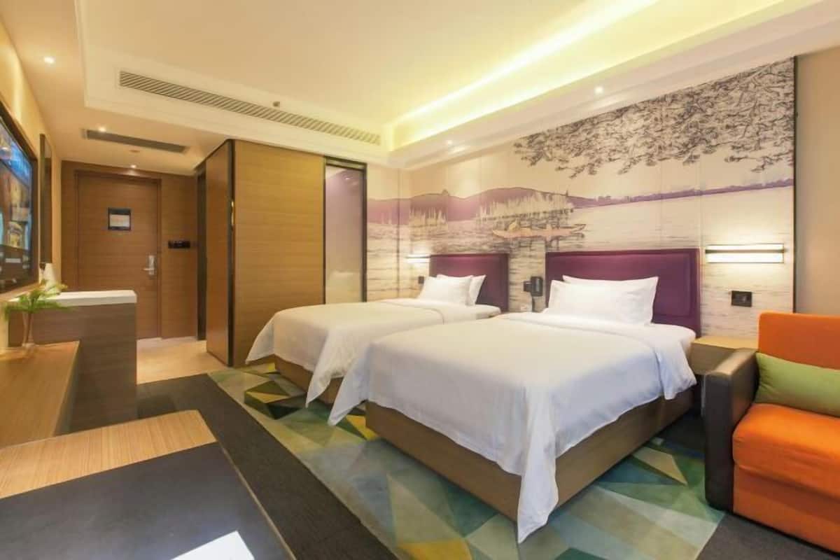 A hotel room with two beds, a sofa, a large wall mural, and a modern design.