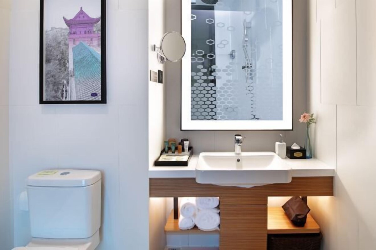 Un baño moderno con inodoro, lavamanos y un cuadro con la imagen de un edificio.
