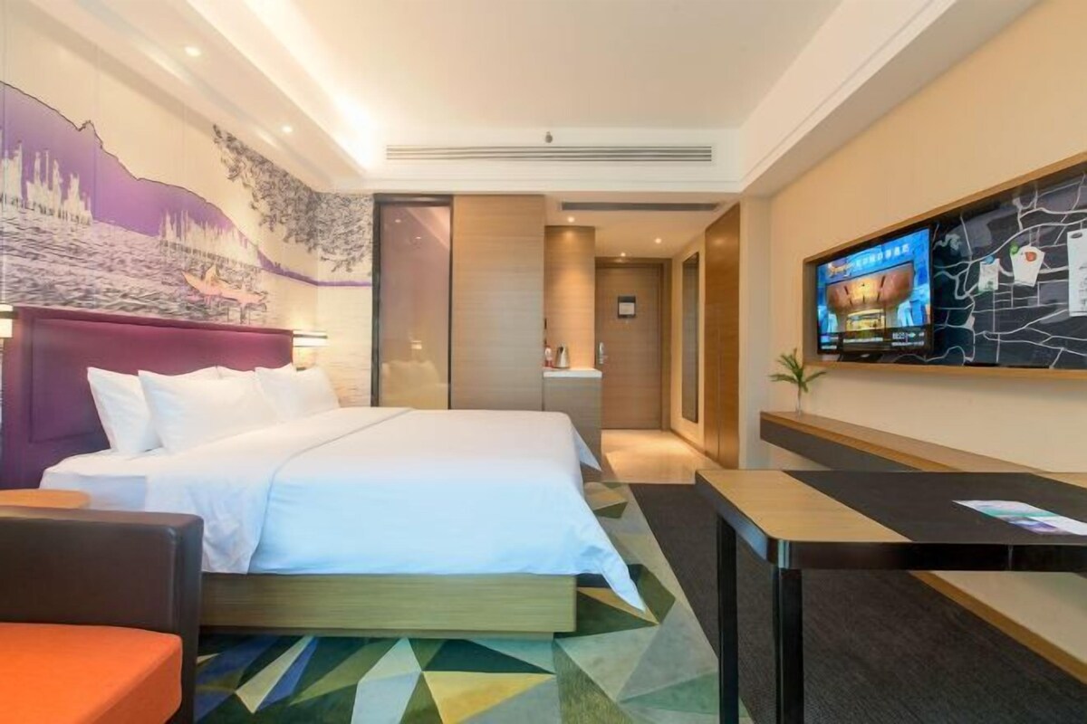 Una habitación de hotel con cama, escritorio, televisor y un mural en la pared.