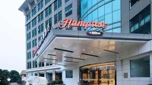 A modern hotel with a prominent "Hampton by Hilton" sign, a glass facade, and a central entrance with a decorative elephant sculpture. - Hampton by Hilton Wuhan Tianhe Airport East (Wuhan)