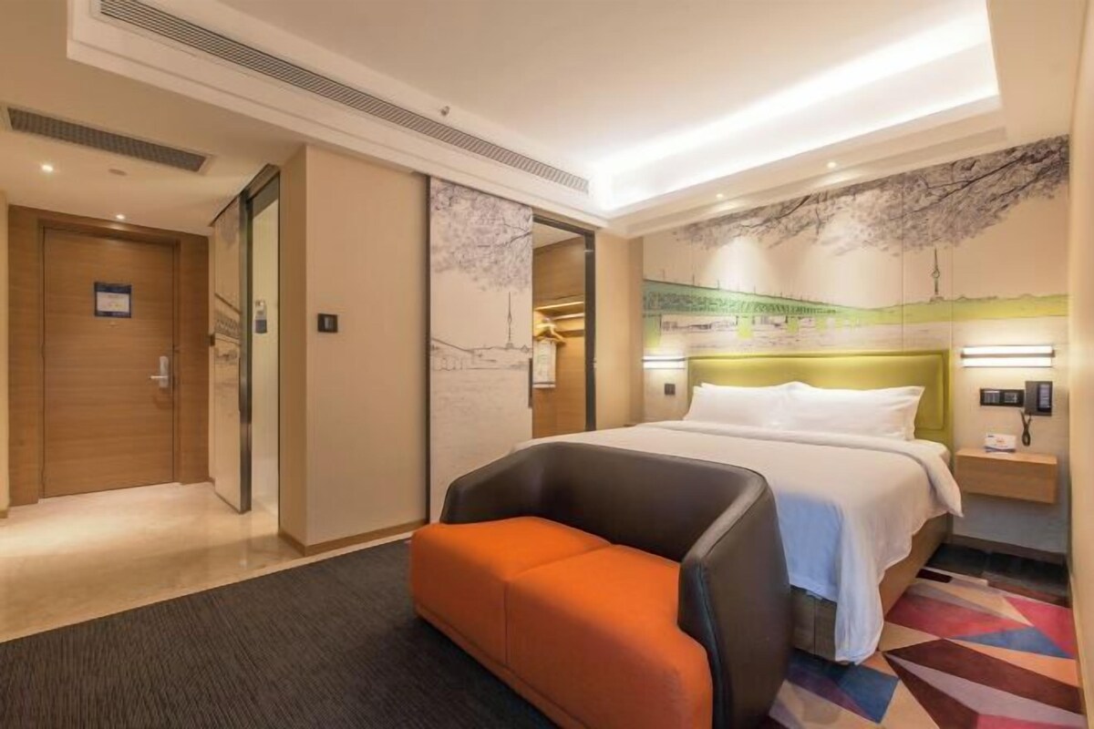 Una habitación de hotel con una cama, un sofá, una mesita de noche y una pared con un mural.