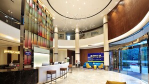 A spacious lobby with a reception desk, seating area, and a large digital display. - Hampton by Hilton Wuhan Tianhe Airport East (Wuhan)