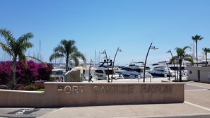 Eine Marina mit vertäuten Yachten, Palmen und einem Schild mit der Aufschrift 'Port Camille Rayon'.