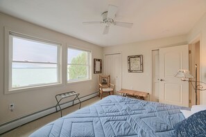 A bedroom with a bed, a chair, a table, a ceiling fan, and a view of the water. - Lakefront De Tour Village Home w/ Deck & Fire Pit! (De Tour Village)
