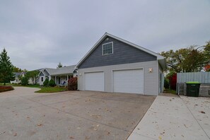 A residential house with a garage, driveway, and a lawn. - Lakefront De Tour Village Home w/ Deck & Fire Pit! (De Tour Village)