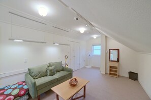 Une pièce avec un canapé vert, une table en bois, un miroir et un ventilateur de plafond.