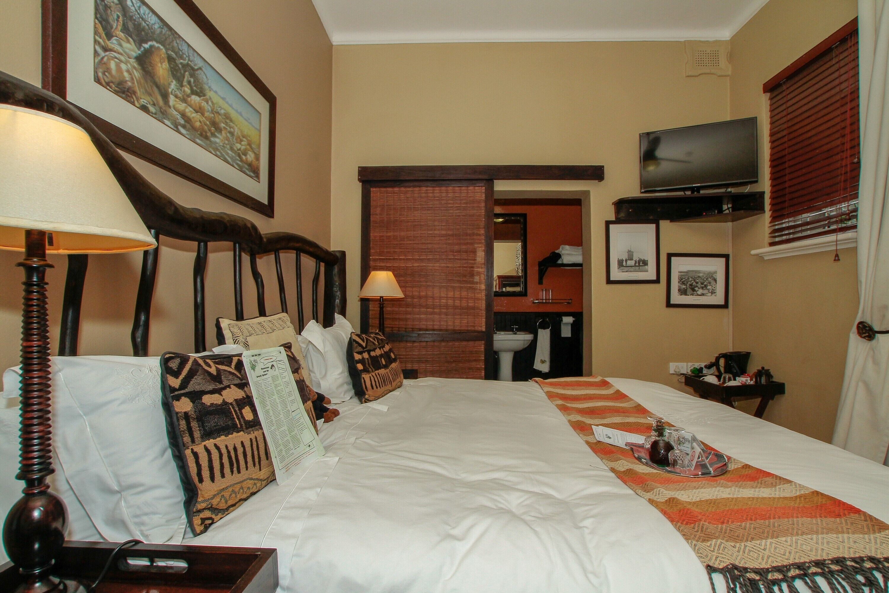 Habitación de hotel con una cama grande, televisión, baño y un cuadro en la pared.