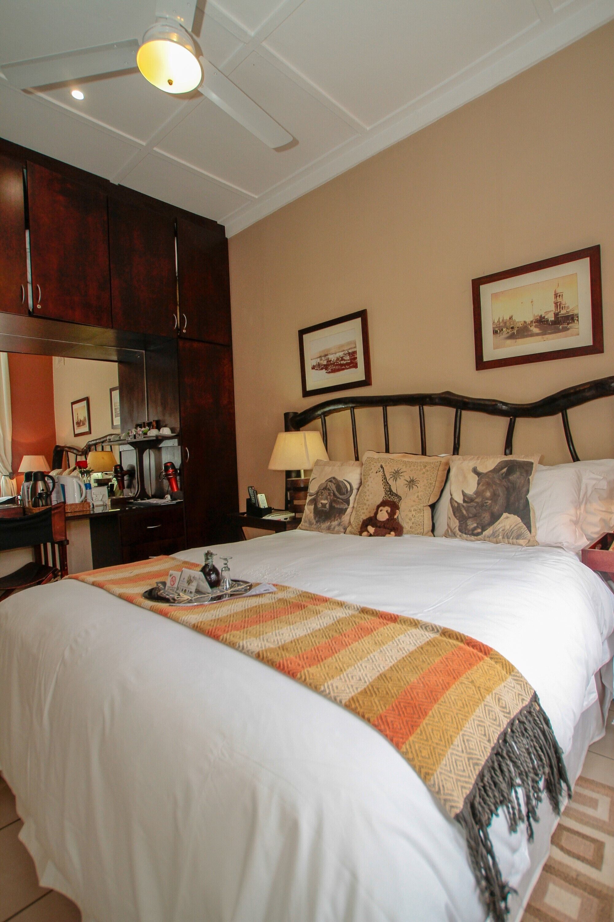 A hotel room with a large bed, a desk with a coffee machine, and a mirror.