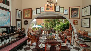 A dining area with a checkered floor, wooden furniture, and framed pictures on the walls.