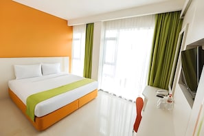 A modern hotel room with a large bed, a desk with a telephone, and a TV.