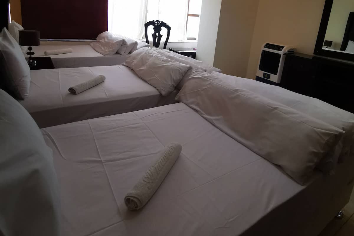 A hotel room with two beds, a desk, a chair, a TV, and a window with a view.