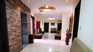 Un vestíbulo moderno con una recepción, un área de espera con sofás y un jarrón decorativo.