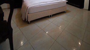 Un dormitorio moderno con una cama grande, un cabecero oscuro, una mesita de noche con lámpara y un armario.