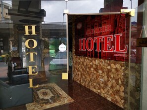 La entrada al Hotel Al Fakher, con un muro de piedra y un cartel grande.