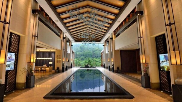 A hotel lobby with a central reflective pool, a reception desk, and a view of greenery through the ceiling. - Hongzhushan Hotels and Resorts Chanyi Shanju (Leshan)