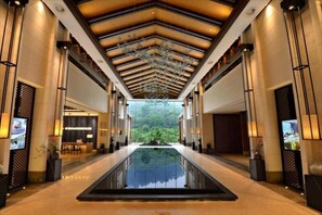 A hotel lobby with a central reflective pool, a reception desk, and a view of greenery through the ceiling. - Hongzhushan Hotels and Resorts Chanyi Shanju (Leshan)