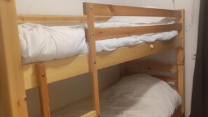 A bunk bed with wooden frames and white bedding.