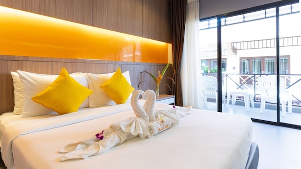 Une chambre d’hôtel avec un lit, des oreillers, une pile de serviettes et une vue sur l’extérieur.