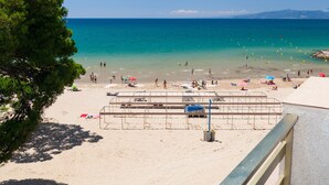 En strand med kristallklart turkost vatten, folk som solar och parasoller.