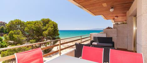 A terrace with a view of the sea, outdoor furniture, and a wooden ceiling.