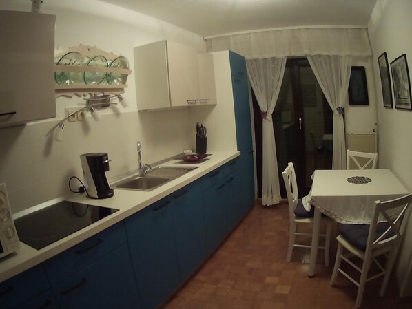 A compact kitchen with a sink, a coffee maker, and a dining area with a table and chairs. - Green Point (Brezovica)