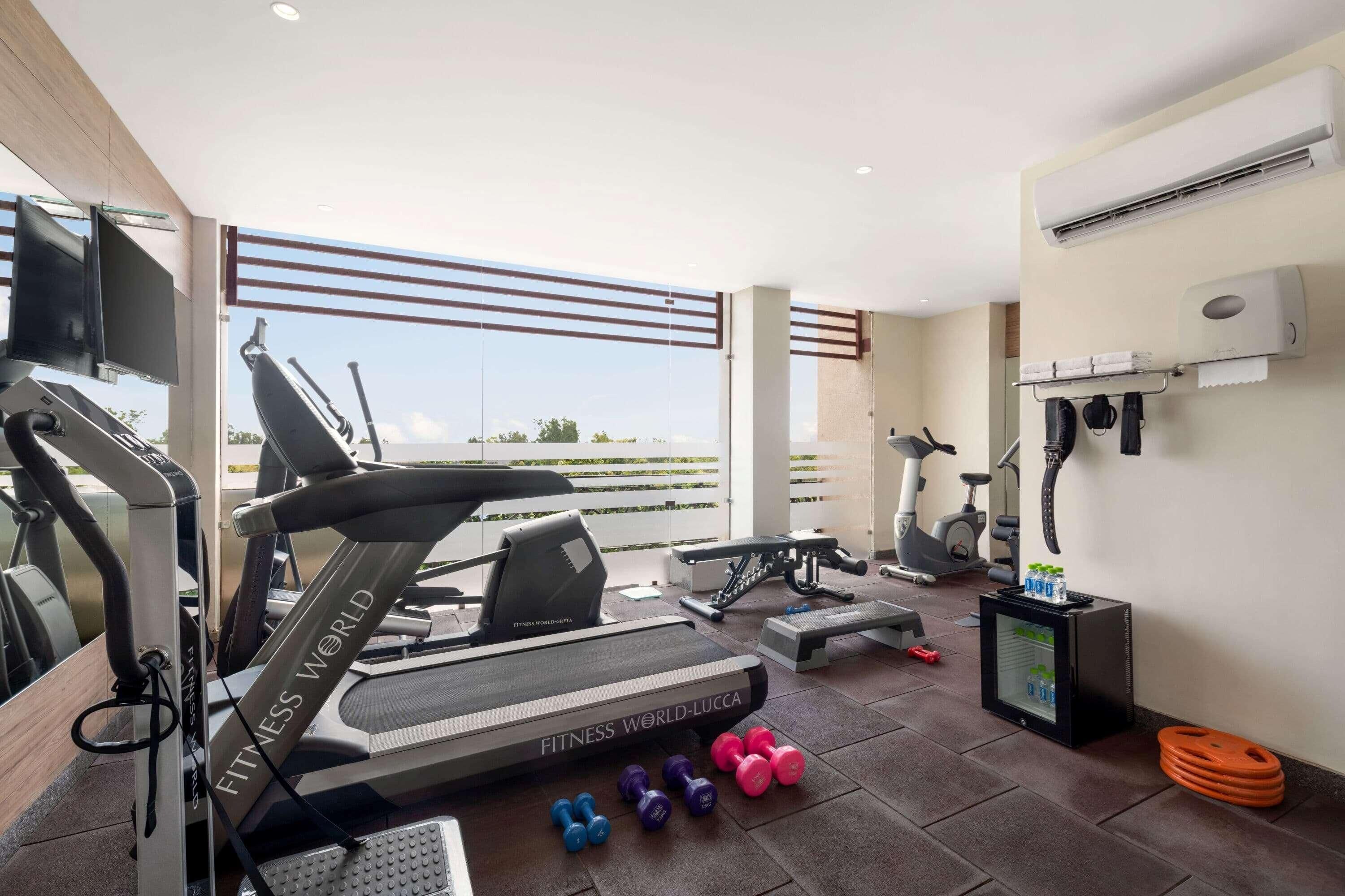 Ein modernes Fitnessstudio mit Laufband, Hanteln und einem Fernsehbildschirm.