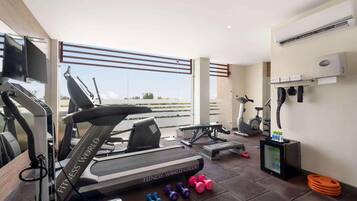 A modern gym with a treadmill, dumbbells, and a TV screen.