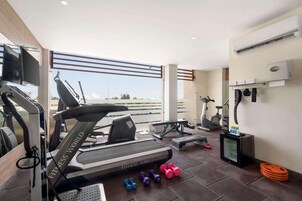 Un gimnasio moderno con cinta de correr, mancuernas y una pantalla de televisión.